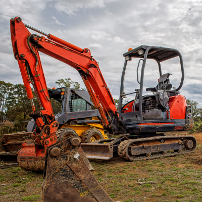 Kubota KX033-4 mini excavator with rubber tracks parked on a dirt jobsite, bucket resting on the ground.
