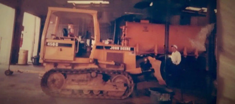 Vintage John Deere crawler dozer operating inside a facility, representing TrackTECH’s long-standing roots in heavy equipment and undercarriage solutions.