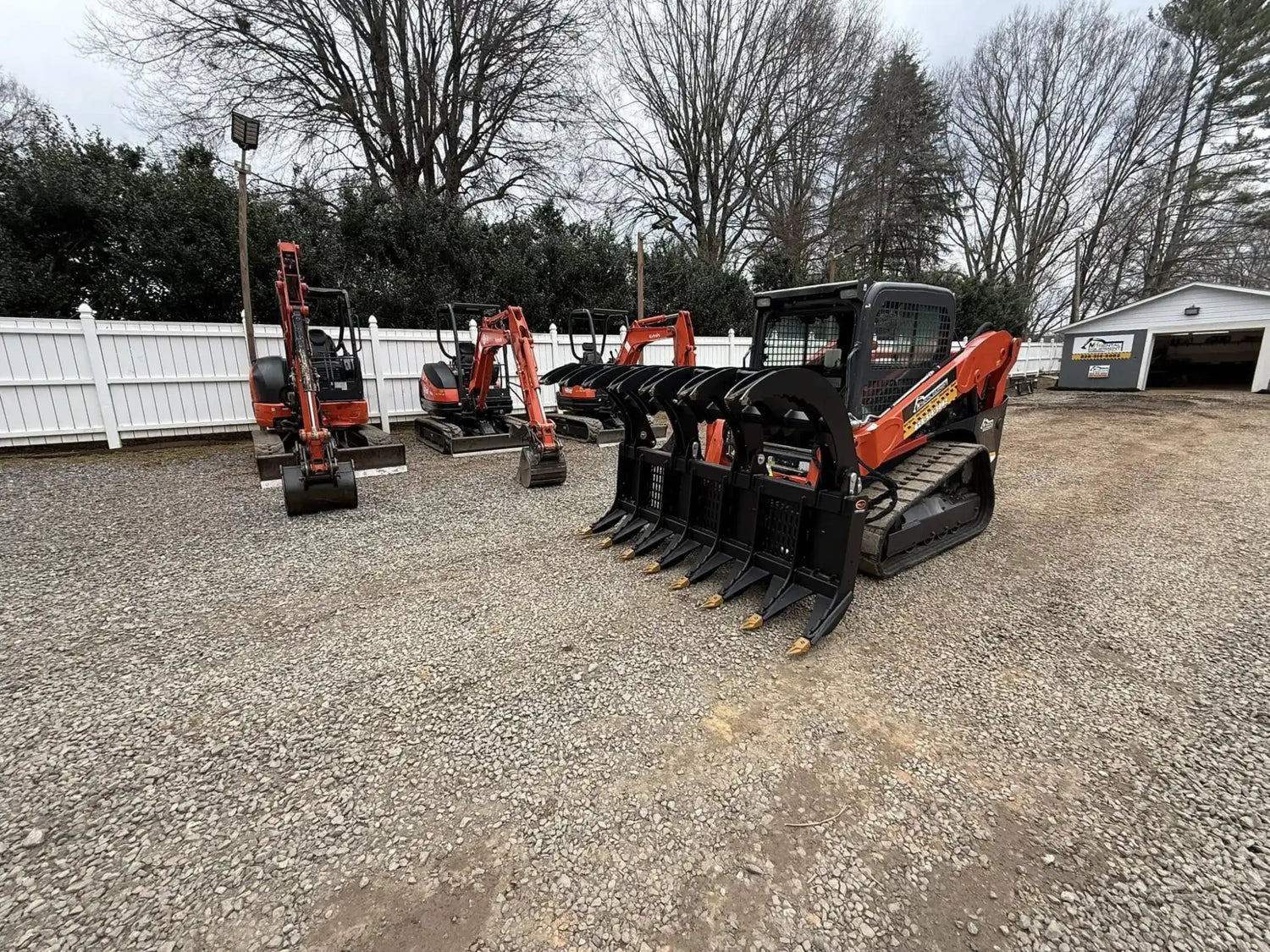 A black and orange compact track loader with a grapple attachment, designed for heavy-duty material handling.