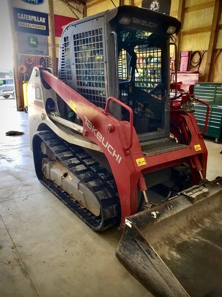 Red and grey Takeuchi compact track loader with a front bucket attachment.