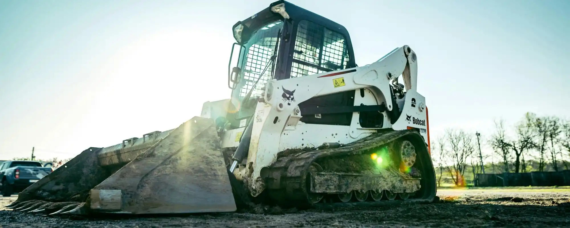 White compact track loader with a wide bucket.