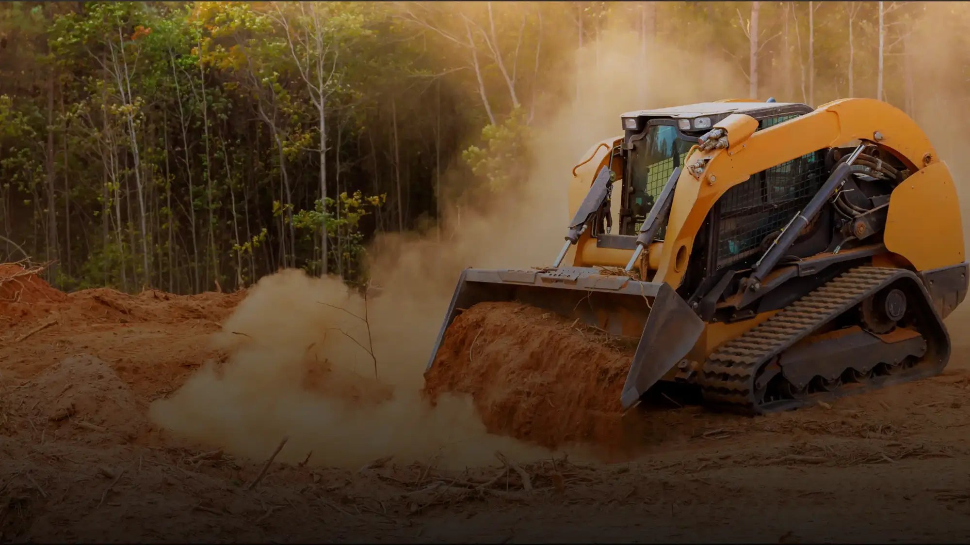 Skid steer loader pushing dirt on a jobsite — heavy-duty rubber tracks kicking up dust, compact track loader in action.