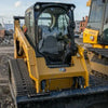 CAT 289D compact track loader with rubber tracks on a construction jobsite — front view of cab, loader arms, and tread.